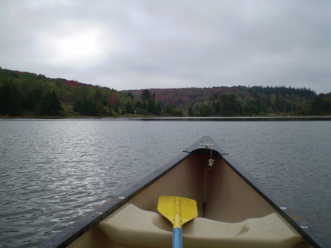 A canoe on Spruce Knob Lake with fall foliage in the distance